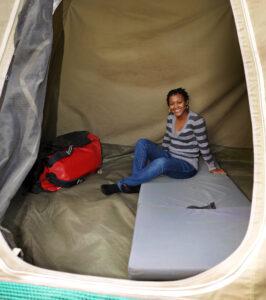 Woman sitting on mattress in tent