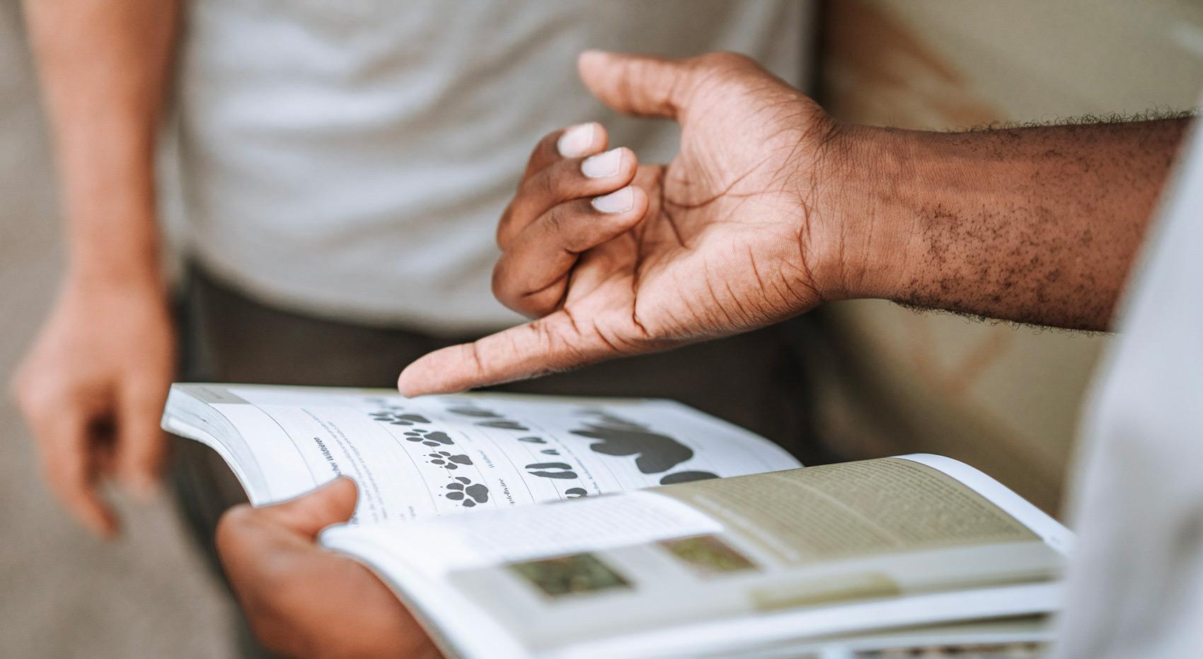 A guide showing a guest images of footprints in a reference book. A guide showing a guest images of footprints in a reference book.