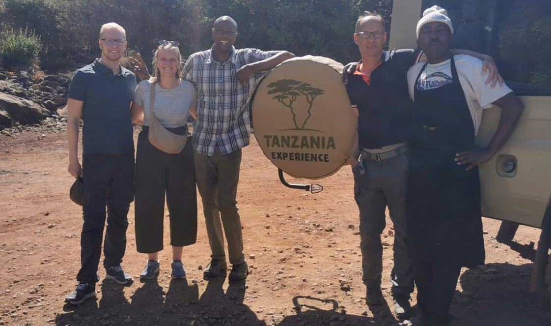 Tanzania-Experience guest poses with guide, Lazaro, and camp chef, Ernest.